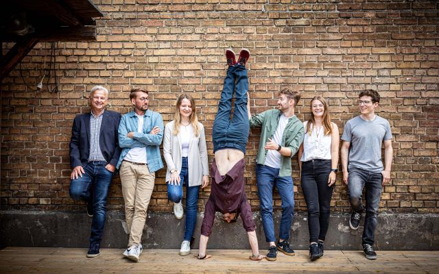 Das sun concept Team, angelehnt an einer Backstein Mauer